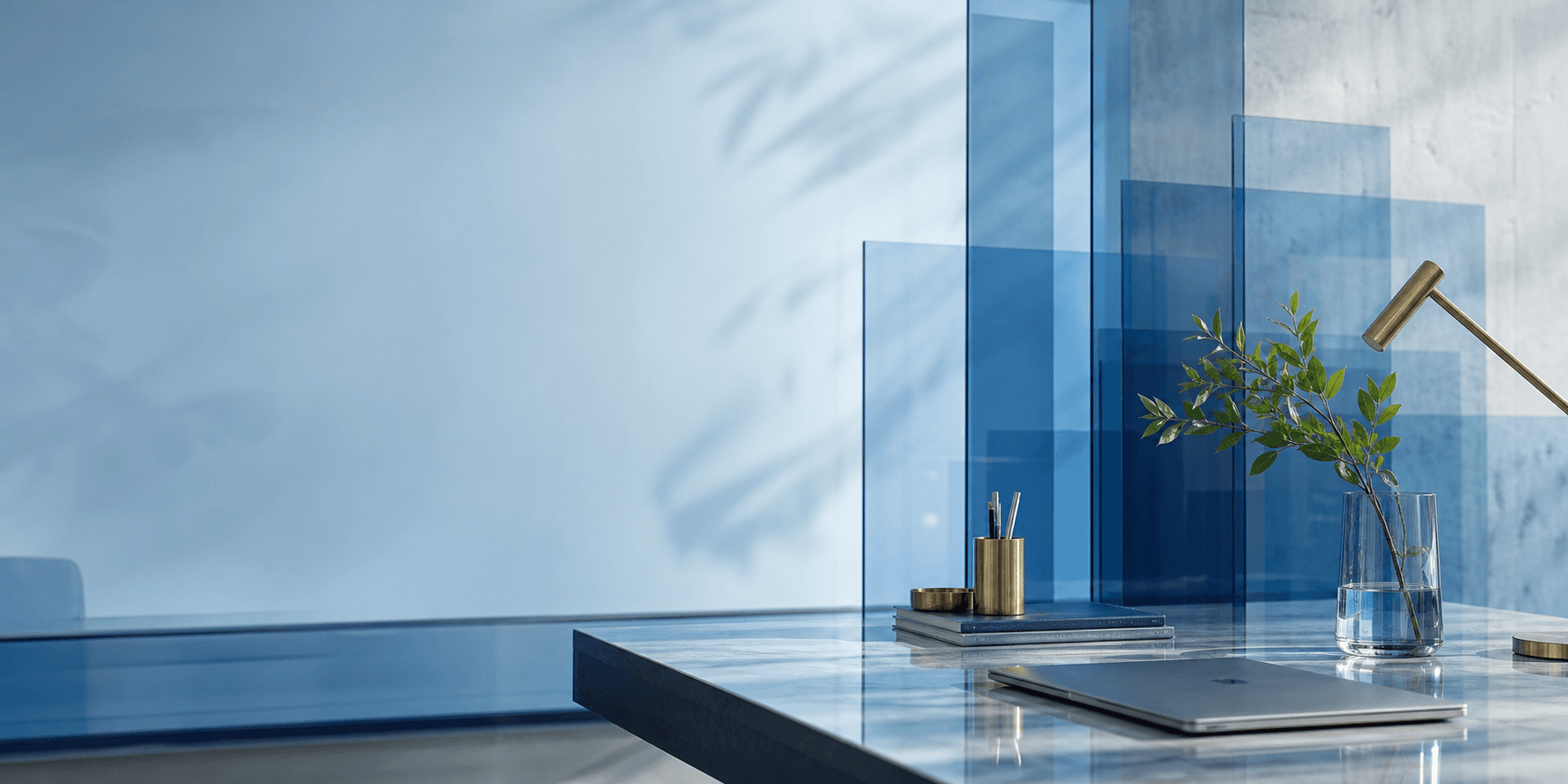 Escena editorial azul con vidrio, escritorio y luz natural